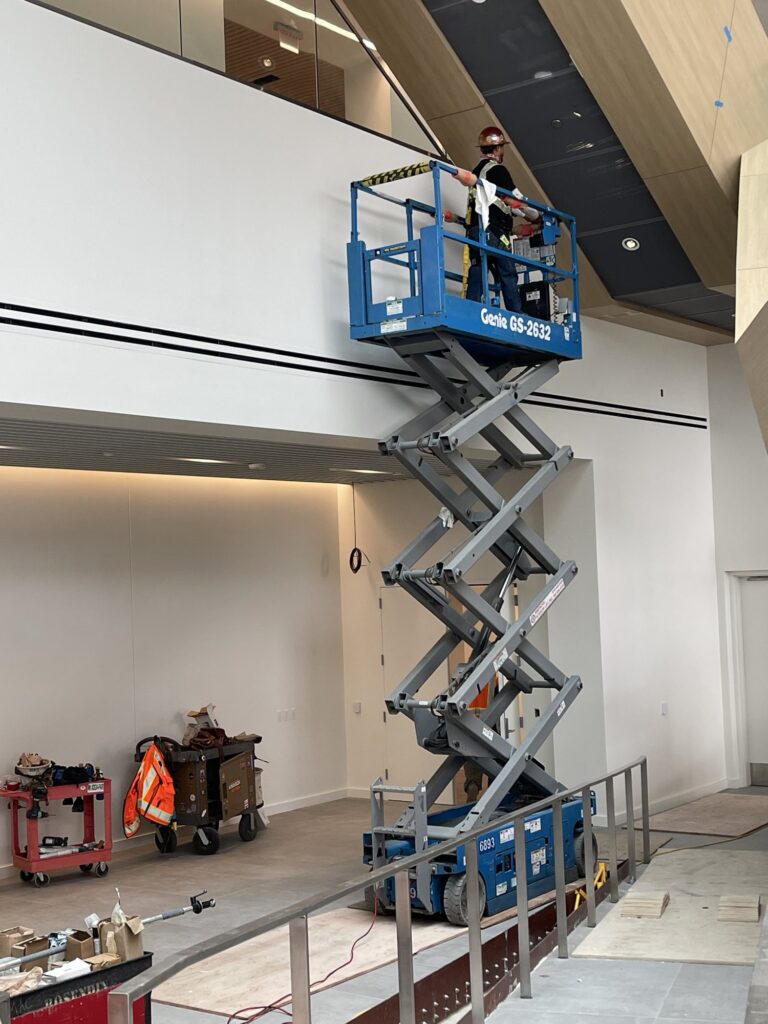Blue Genie GS-2632 scissor lift extended to a mezzanine with a worker on the platform
