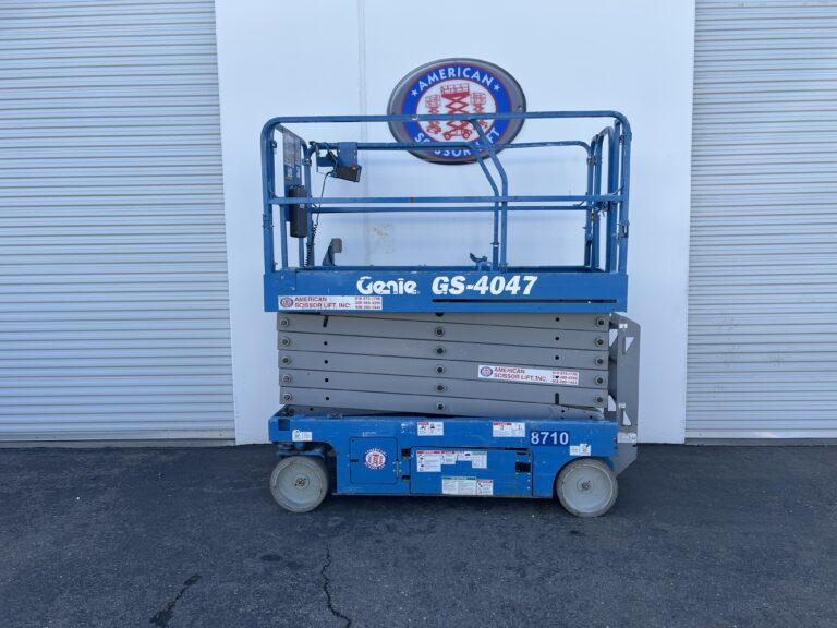 Used 2015 blue Genie GS-4047 electric scissor lift with its platform lowered in front of an American Scissor Lift building