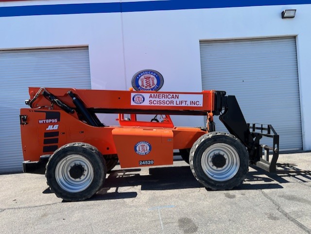 Used 2015 orange SkyTrak 8042 telehandler with fork carriage, parked in front of a warehouse, from the American Scissor Lift rental fleet